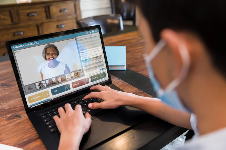 A school pupil looking at his teacher through a laptop during an online lesson.