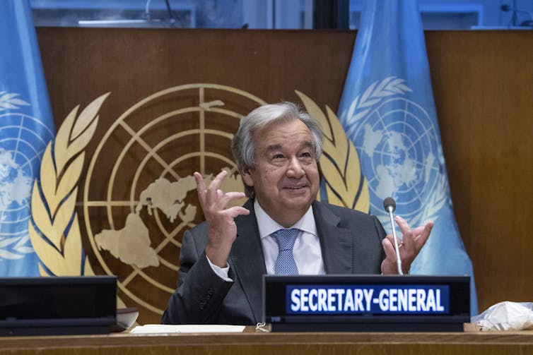 UN Secretary-general Antonio Guterres gestures with his hands while addressing a meeting with the UN emblem in the background