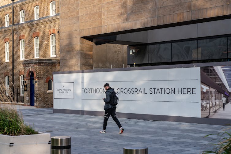 Man walking past sign which says