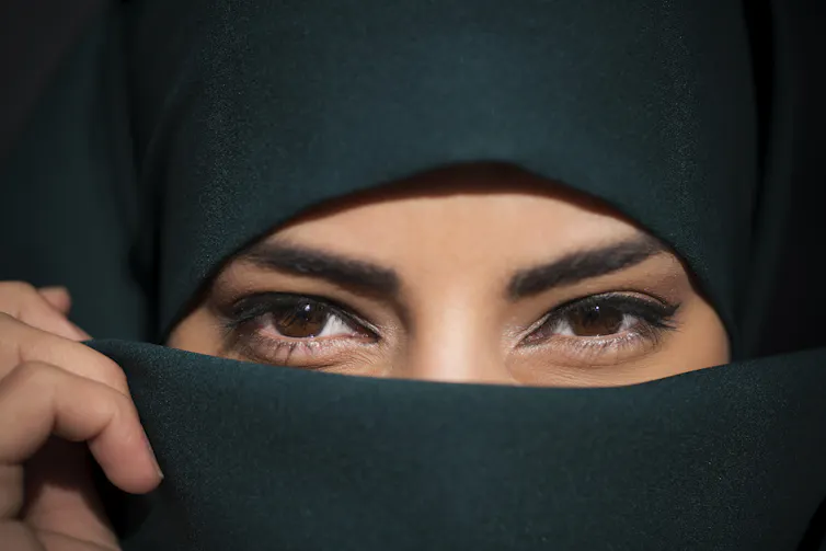Close up of a woman wearing a niqab, who is clearly smiling.
