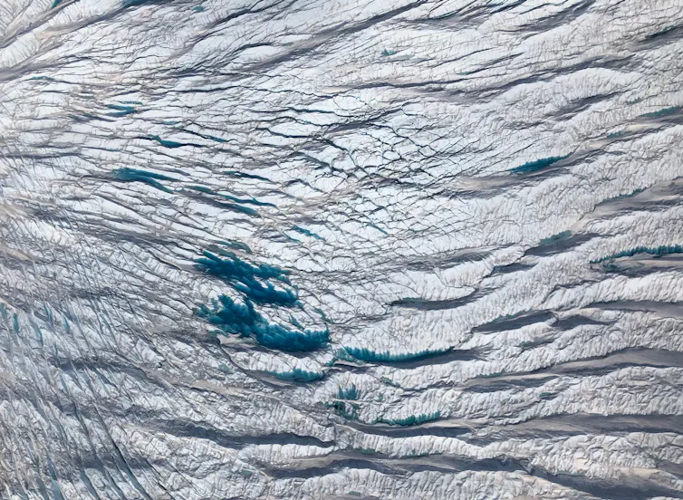 An aerial view of a pond on the top of a glacier formed by melting ice.