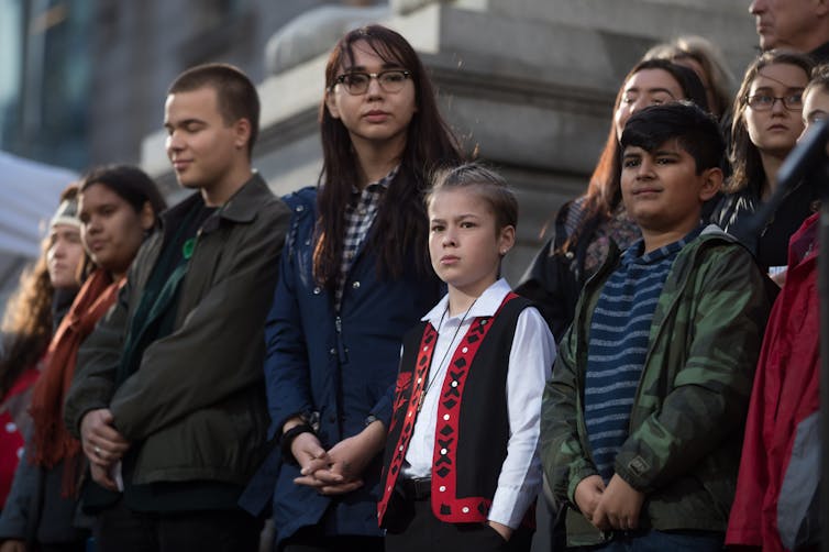 A group of children and teenagers stand in front of a building