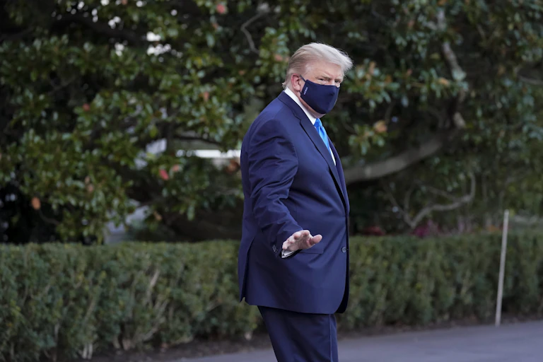 Donald Trump wears a mask as he waves to members of the media.