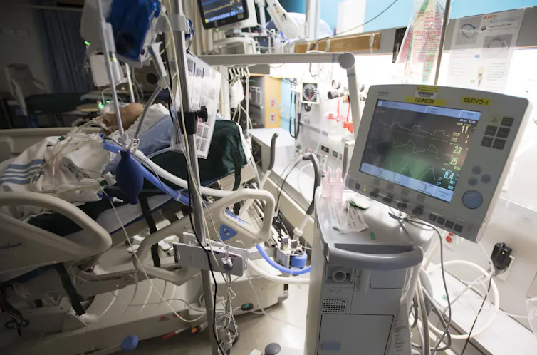 A patient is attached to a ventilator in a hospital intensive care unit.