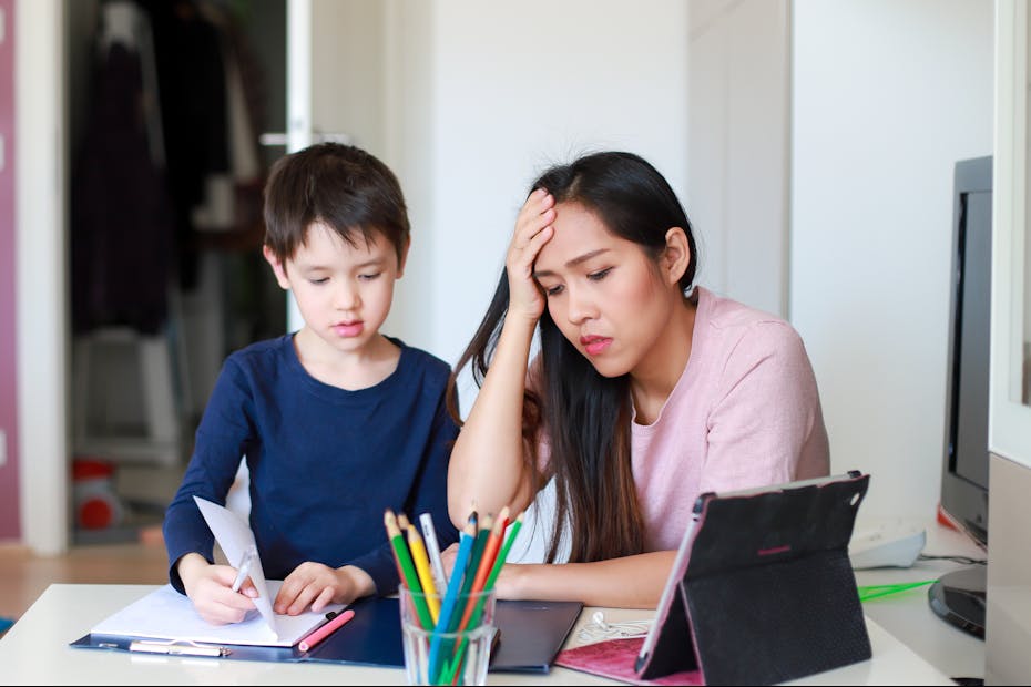 Stressed mother helping her son with school work