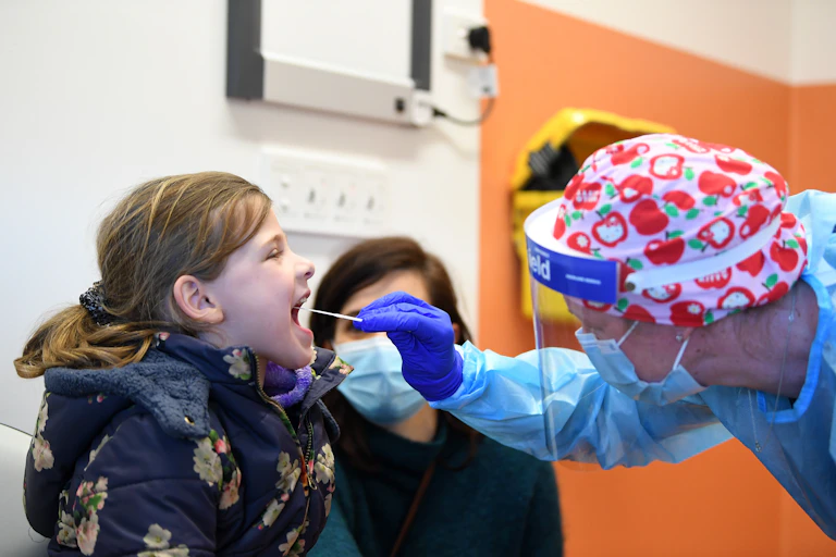 A girl has her mouth swabbed by a health worker as part of a COVID test.
