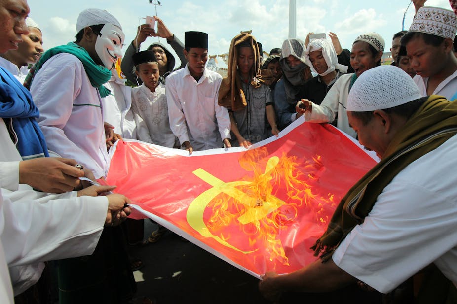 Pengunjuk rasa membakar kain bersimbol komunis dalam sebuah aksi di depan kantor Gubernur Jawa Timur, Surabaya, Jawa Timur.