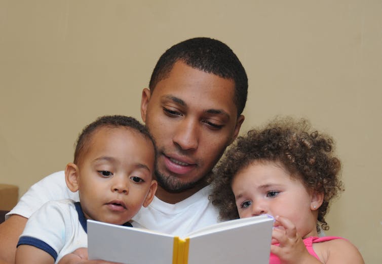 Man reads to two children.