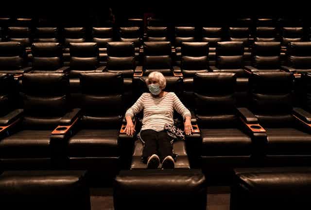 A woman sits in an empty Regal theater in California.