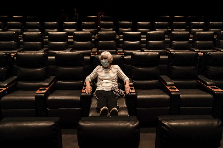 A woman sits in an empty Regal theater in California.