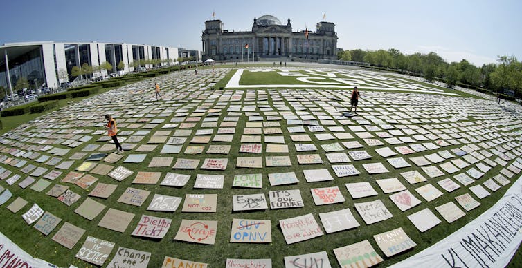 Placards cover a grassy field in front of government buildings in Berlin.