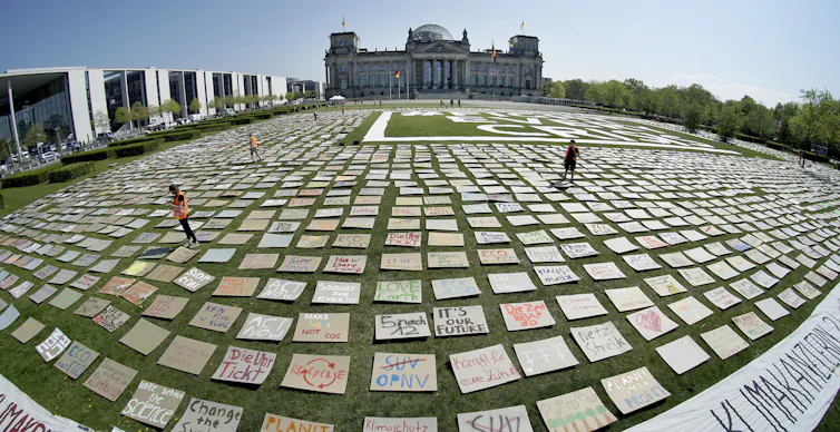 Placards cover a grassy field in front of government buildings in Berlin.