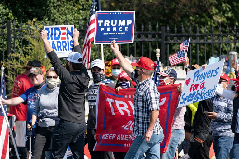 A lone Biden supporter holds a sign as as supporters of Donald Trump rally outside of Walter Reed Medical Center.