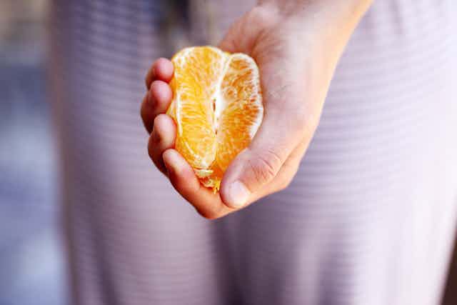 Woman's hand holding a quarter of a mandarin.
