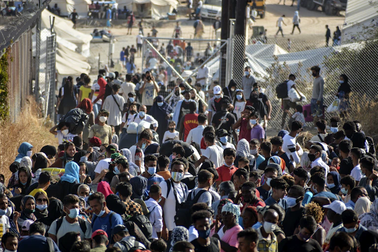 A large crowd of refugees, mostly wearing face masks.