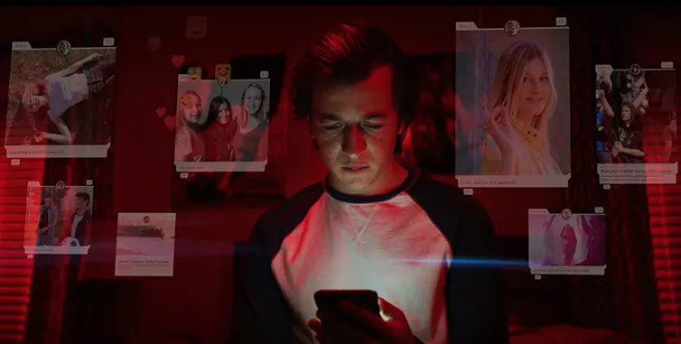A character from The Social Dilemma looks at his phone.
