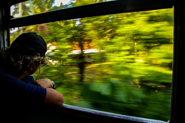 Man looking out of train window as scenery speeding by