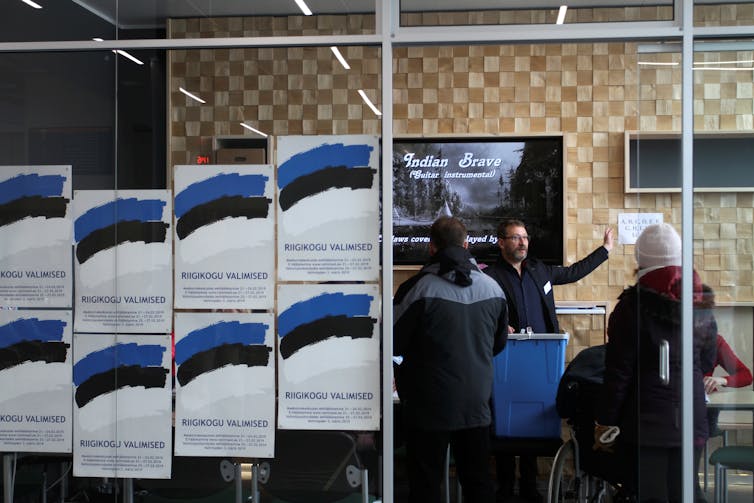 Posters and people outside a polling station.
