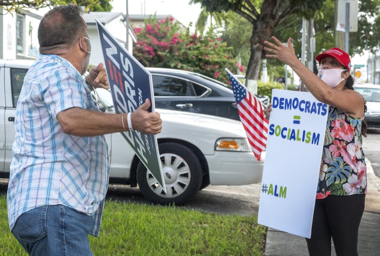 Supporters of Joe Biden and Donald Trump both carrying placards and gesturing at each other.