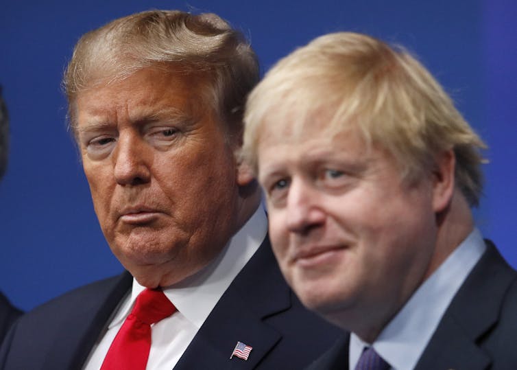 Two middle aged men in suits posing together.