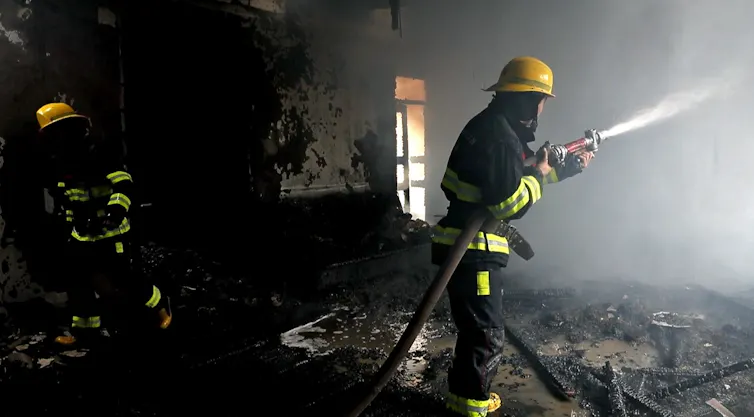 Two firemen, one with hose.