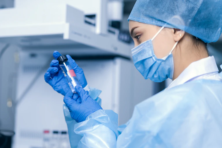A female scientist in a lab looking at a vial of fluid