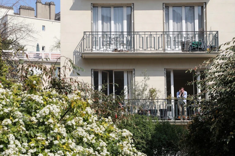 Un homme sur son balcon à Paris.
