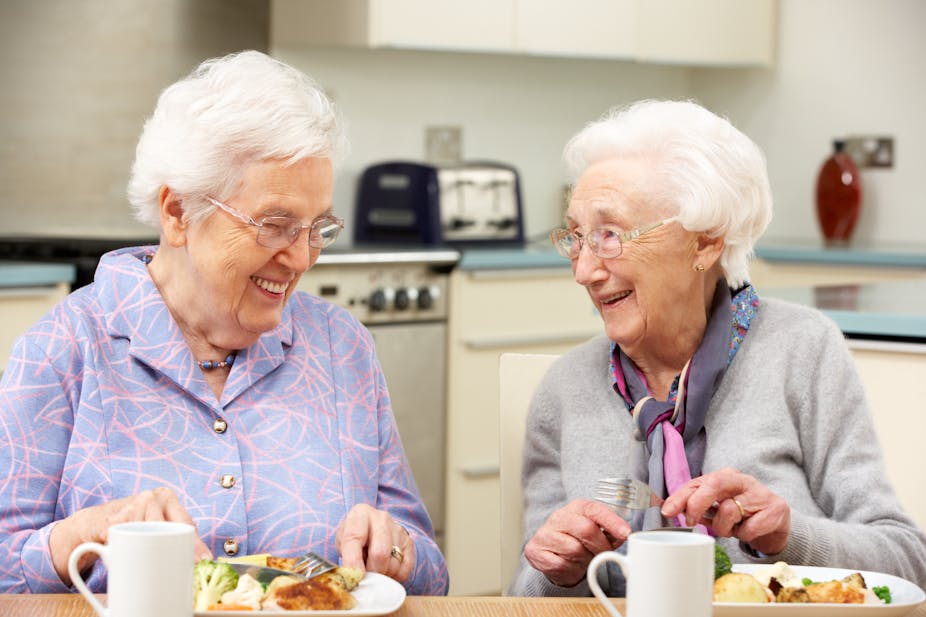 Two older women eat lunch together.