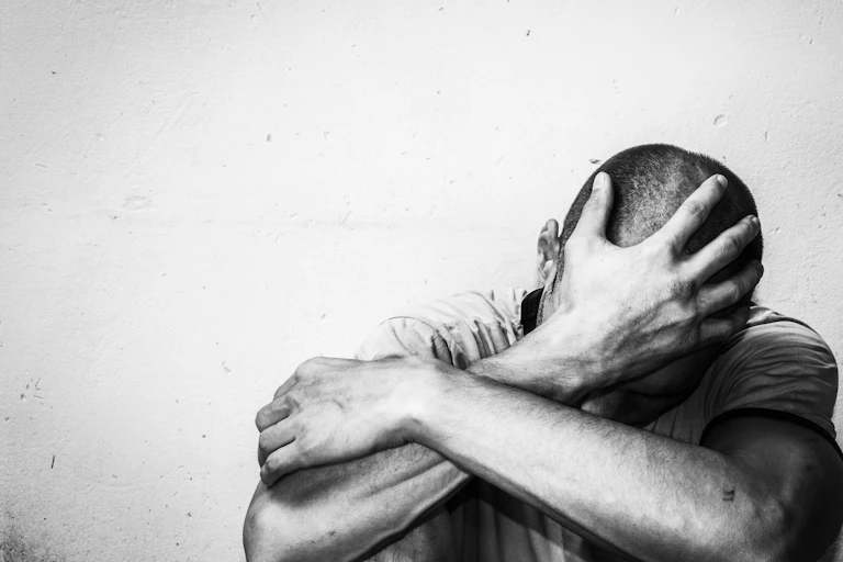 Hombre abatido se sujeta la cabeza con la palma abierta.