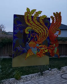 A square image of fluttering silks superimposed atop a backyard fence.