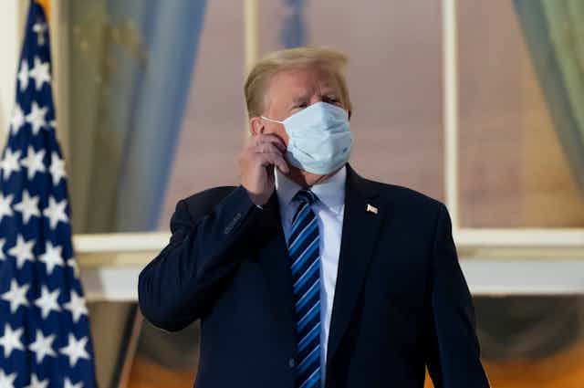 President Donald Trump removes his mask.