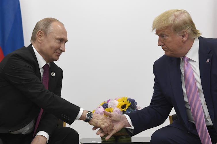 Vladimir Putin and Donald Trump shake hands