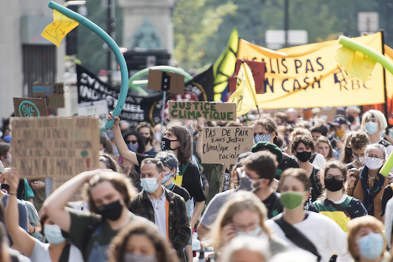 Large group of people marching, while holding signs and wearing masks