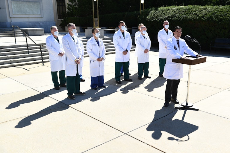 Physicians in white coats give a press conference