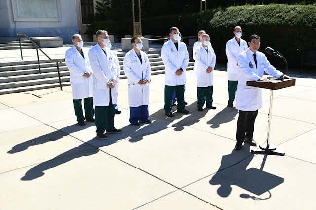 Physicians in white coats give a press conference