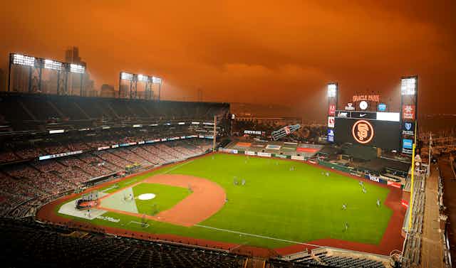 baseball field with reddish hazy sky caused by wildfire smoke.