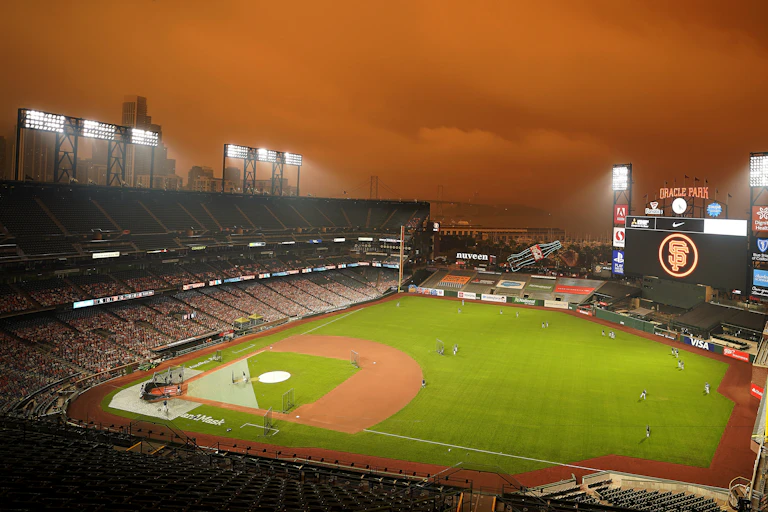 baseball field with reddish hazy sky caused by wildfire smoke.