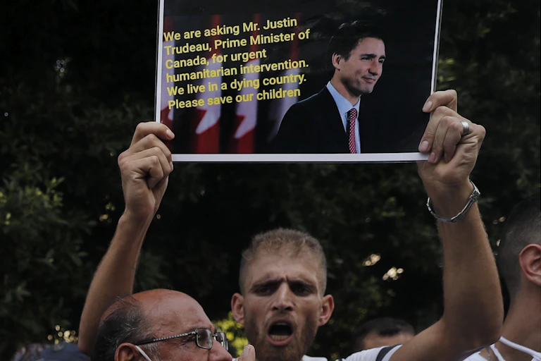 A man holds up a sign pleading for help from Justin Trudeau.