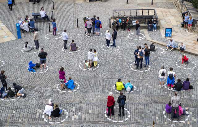 Visitors to Edinburgh socially distance in circles painted on the ground.