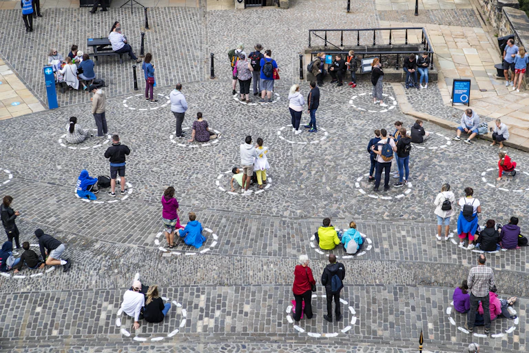 Visitors to Edinburgh socially distance in circles painted on the ground.