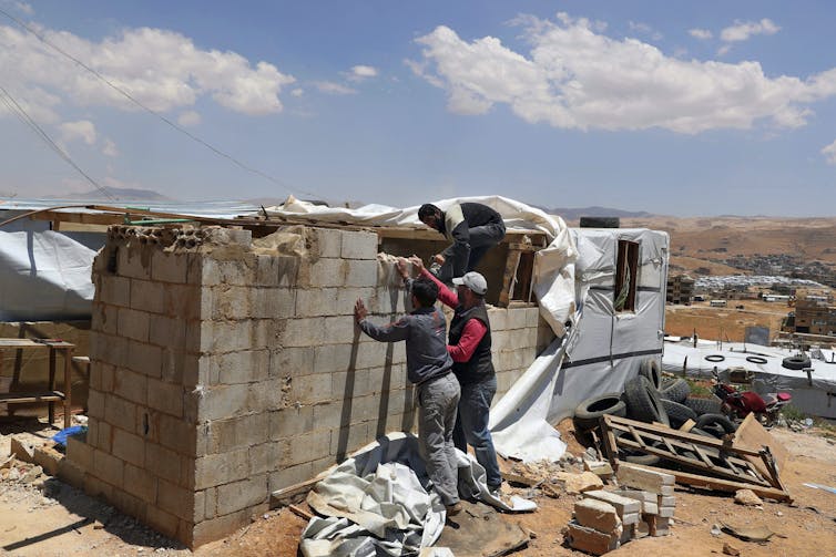 Men work to take down a concrete block wall.