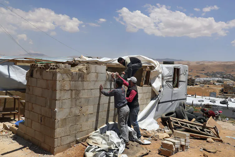 Men work to take down a concrete block wall.