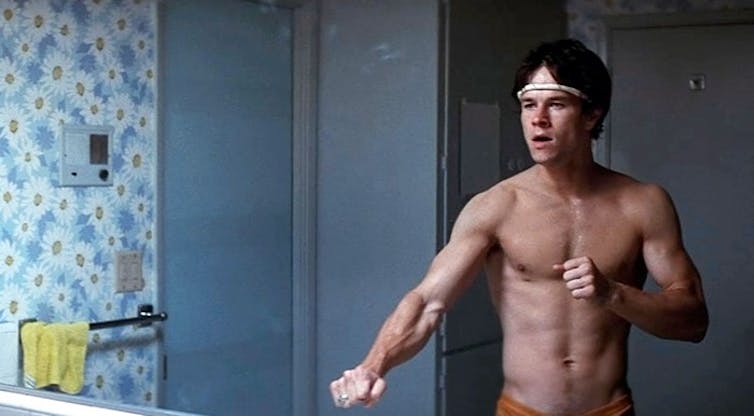 Dirk Diggler, played by Mark Wahlberg, poses in front of a mirror shirtless.