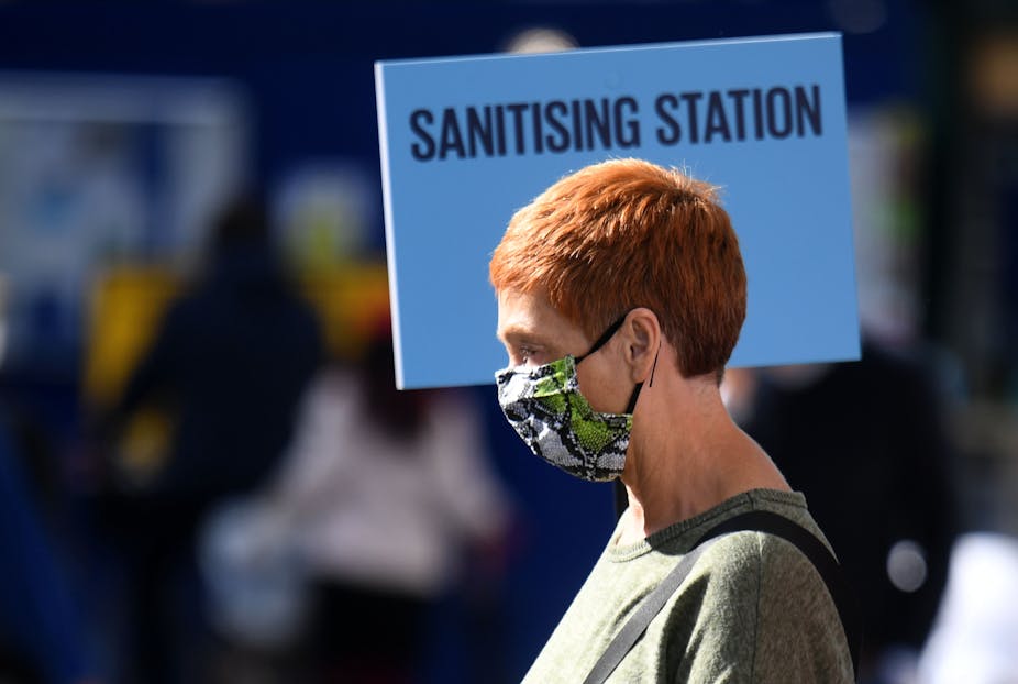 Woman in London walking past sanitising station