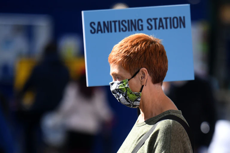 Woman in London walking past sanitising station