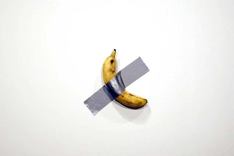 Banana taped to wall with silver duct tape.