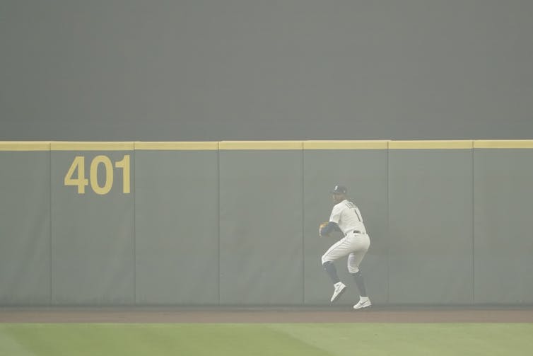 Kyle Lewis prepares to throw the ball back to the infield after making a catch as the air is filled with wildfire smoke during the first baseball game of a doubleheader against the Oakland Athletics, Monday, Sept. 14, 2020, in Seattle.