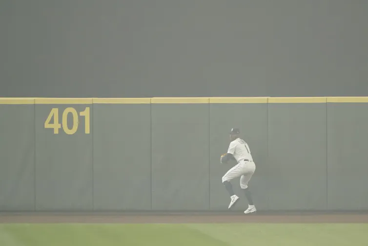 Kyle Lewis prepares to throw the ball back to the infield after making a catch as the air is filled with wildfire smoke during the first baseball game of a doubleheader against the Oakland Athletics, Monday, Sept. 14, 2020, in Seattle.