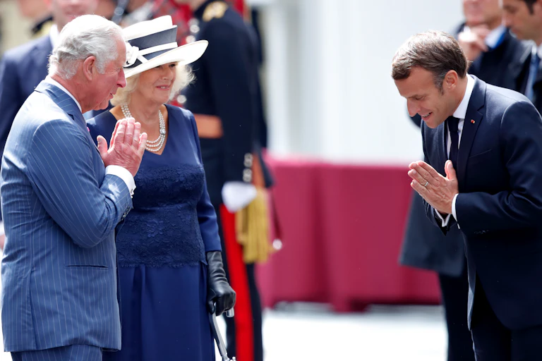 Prince Charles and Emmanuel Macron greet each other with prayer hands