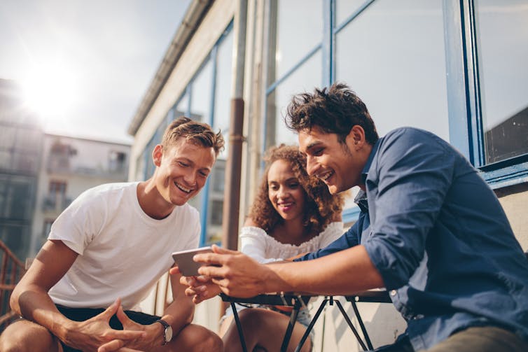 Three young people looking at a mobile phone screen